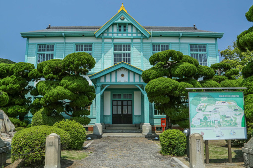 The Awashima Maritime Museum, a 2-story wooden building that has been painted a bright teal.