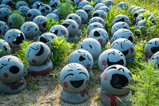 Many statues made of buoys that look like jizo statues. The statues are arranged in rows. No two have the same face or expression.