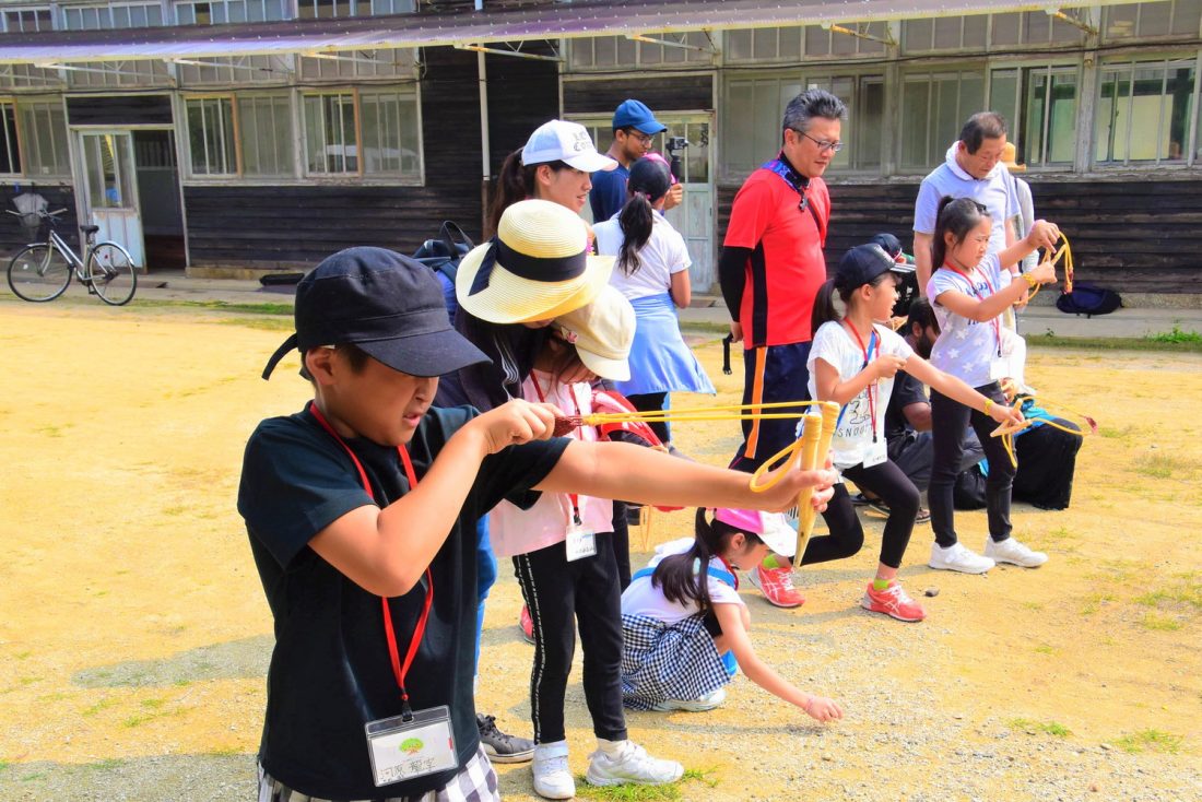 パチンコを使って石の試し打ちをする子どもたち。ワークショップでは、自然とともに生きる